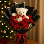 Load image into Gallery viewer, Bouquet of red roses with a white teddy bear in the center, set against a blurred festive background.
