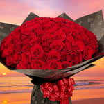 Load image into Gallery viewer, Bouquet of red roses with a sunset beach background
