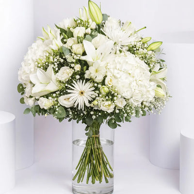 Bouquet of white flowers in a clear vase on a white background