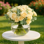 Load image into Gallery viewer, Bouquet of white roses in a clear vase on a white table outdoors.
