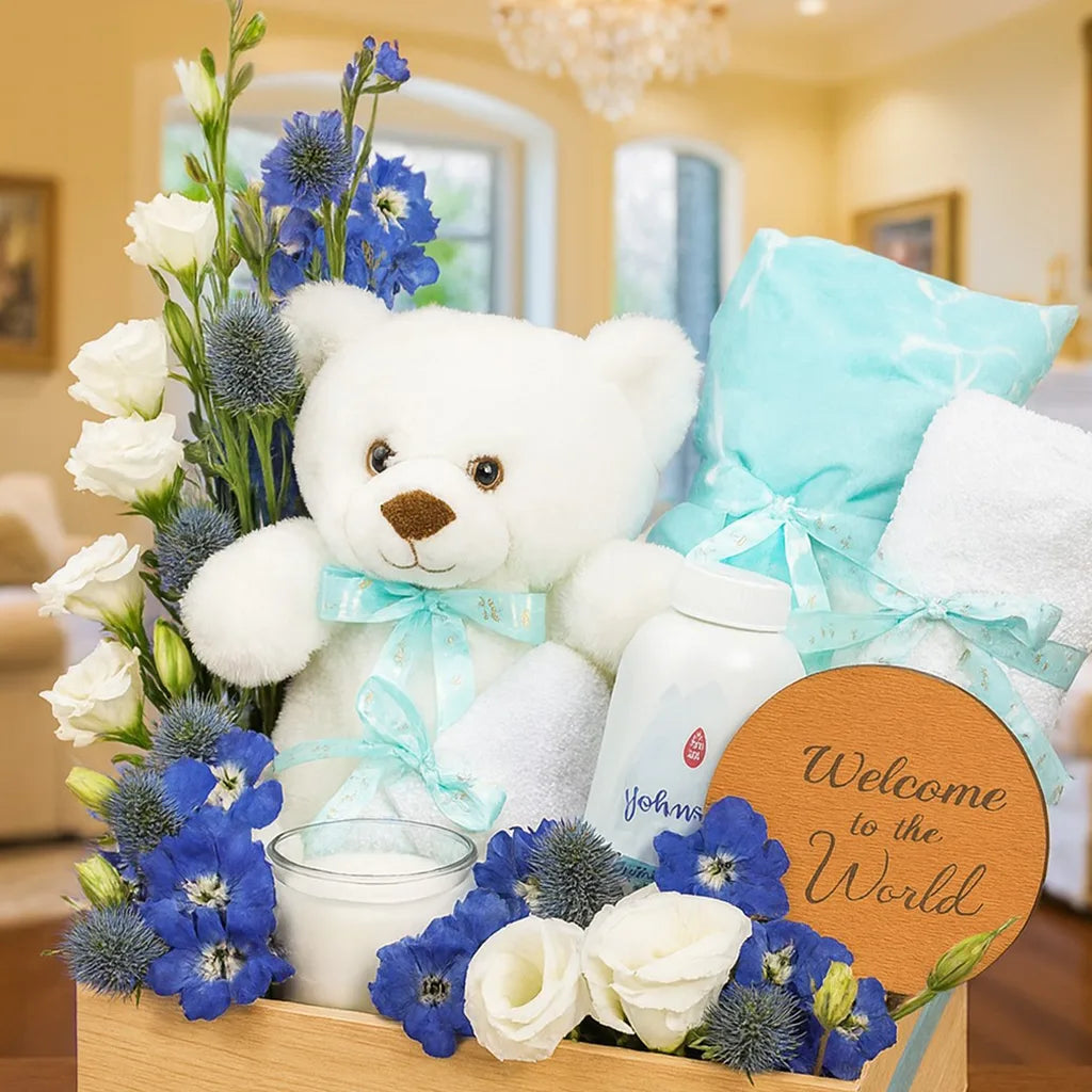Greeting set with teddy bear, flowers, and 'Welcome to the World' sign in a decorative box.