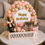 Load image into Gallery viewer, Birthday gift basket with balloons, wine, and decorative items on a table.
