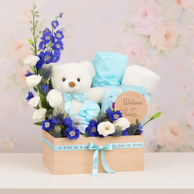 Teddy bear and flowers in a box with a personalized card on a soft floral background