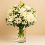 Load image into Gallery viewer, Bouquet of white flowers in a clear vase on a beige background
